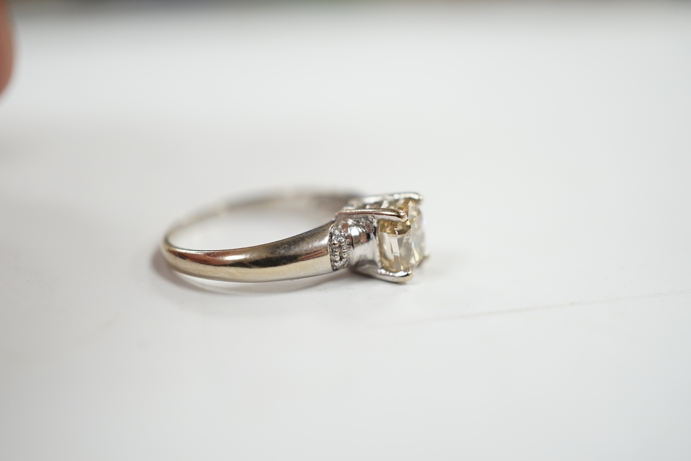 A 750 white metal and single stone oval cushion cut diamond ring, with four stone diamond chip set shoulders, size K, gross weight 3.3 grams.